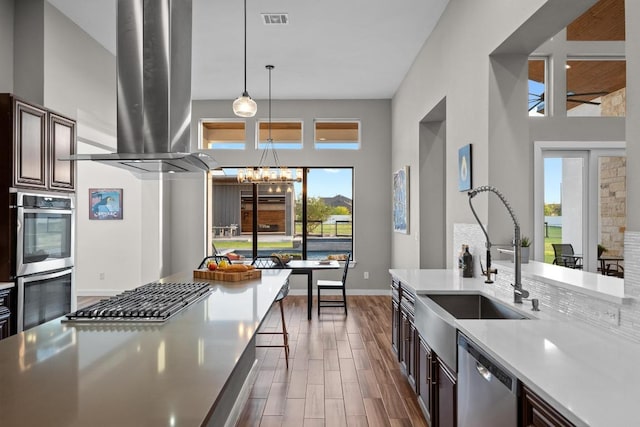 kitchen featuring a sink, wood finished floors, visible vents, stainless steel appliances, and island range hood