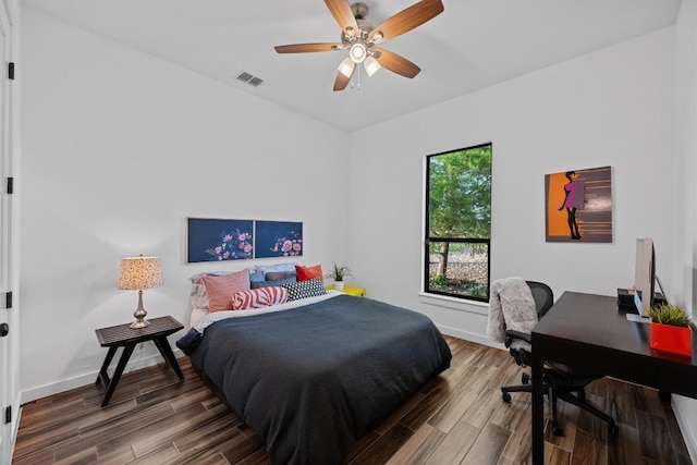 bedroom with baseboards, visible vents, and wood finished floors