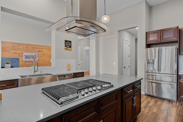 kitchen with tasteful backsplash, island range hood, stainless steel appliances, a sink, and light wood finished floors