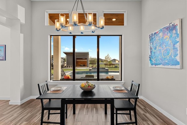 dining area featuring baseboards, wood finished floors, and a chandelier