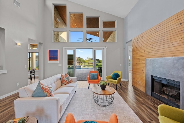 living area with high vaulted ceiling, a fireplace, wood finished floors, baseboards, and visible vents