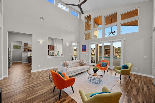 living area featuring baseboards, visible vents, ceiling fan, and wood finished floors