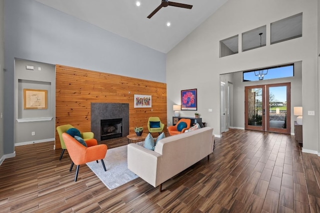 living room with a ceiling fan, dark wood-style floors, wooden walls, and an accent wall