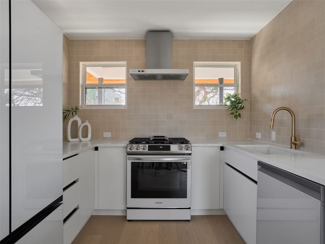 411 Krebs, Austin, TX 78704 - kitchen featuring stainless steel gas range, wall chimney exhaust hood, dishwashing machine, and white cabinetry