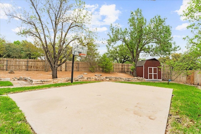 view of basketball court with a storage unit, a fenced backyard, and basketball court