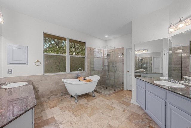 12452 Fairfax Ridge Pl, Austin, TX 78738 - full bath featuring two vanities, a stall shower, a freestanding bath, tile walls, and stone finish flooring
