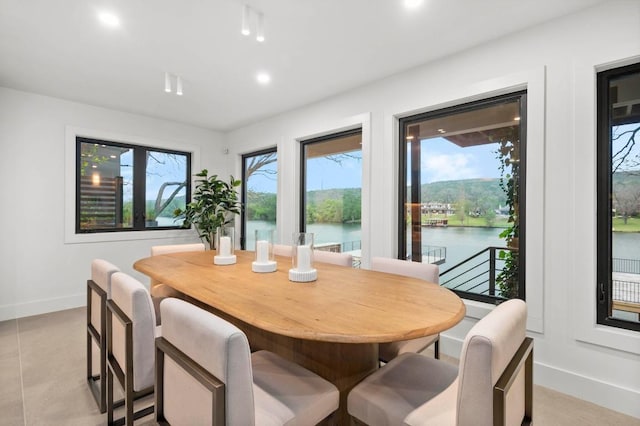 dining area with recessed lighting, a water view, and baseboards