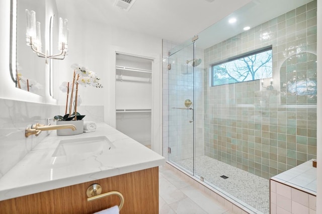 full bathroom with a shower stall, tile patterned flooring, visible vents, vanity, and a walk in closet