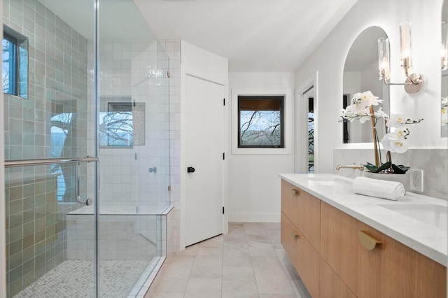 bathroom with baseboards, a sink, a shower stall, and double vanity