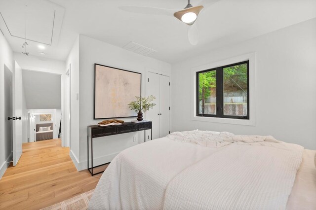 bedroom featuring wood finished floors, visible vents, a ceiling fan, baseboards, and attic access