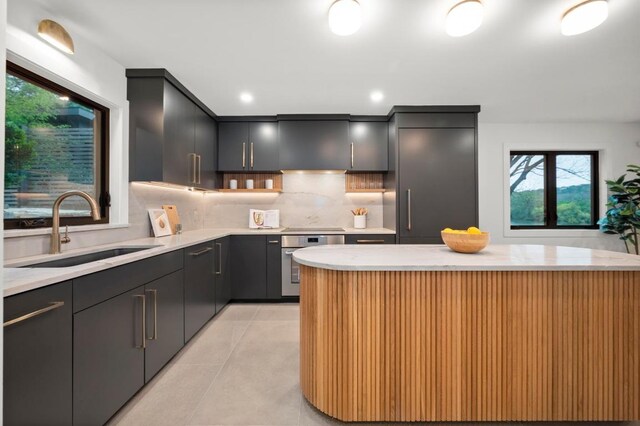 kitchen featuring stainless steel oven, decorative backsplash, a sink, and light countertops