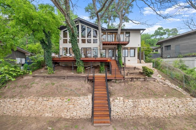 rear view of house featuring stairway, a wooden deck, a balcony, and stucco siding