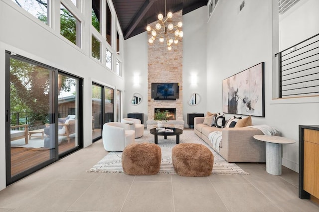 living area with plenty of natural light, visible vents, a towering ceiling, and a stone fireplace