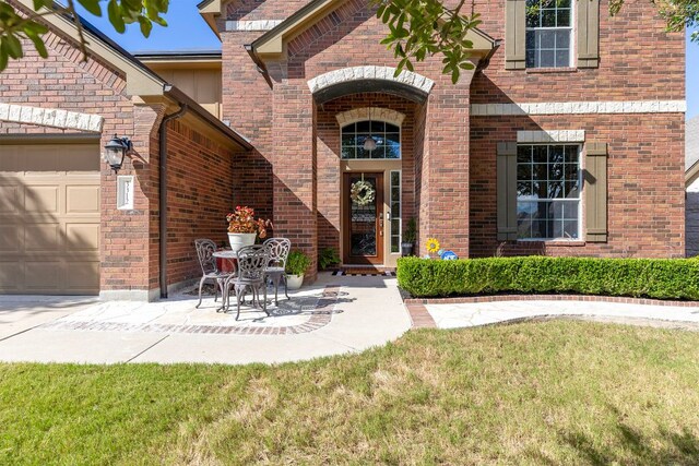3312 Cortes Pl, Round Rock, TX 78665 - property entrance with brick siding, an attached garage, and a yard