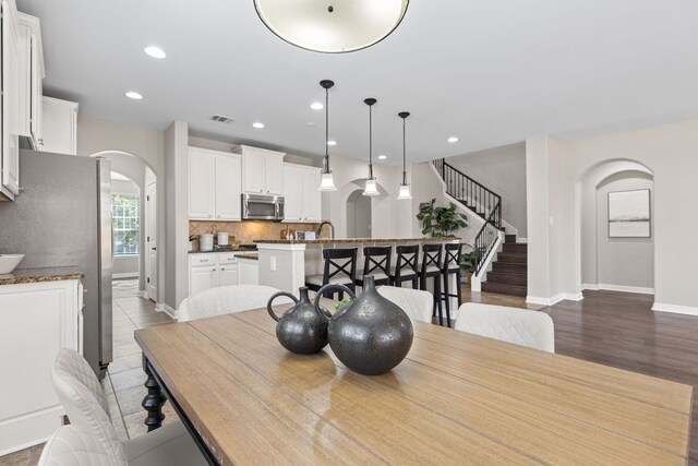 3312 Cortes Pl, Round Rock, TX 78665 - dining space featuring arched walkways, stairway, recessed lighting, and wood finished floors