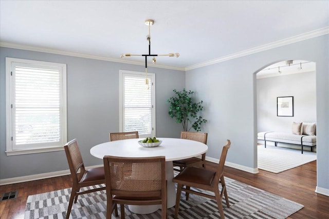 2210 Meadowbrook Dr, Austin, TX 78703 - dining area with dark wood-type flooring, a chandelier, arched walkways, and crown molding