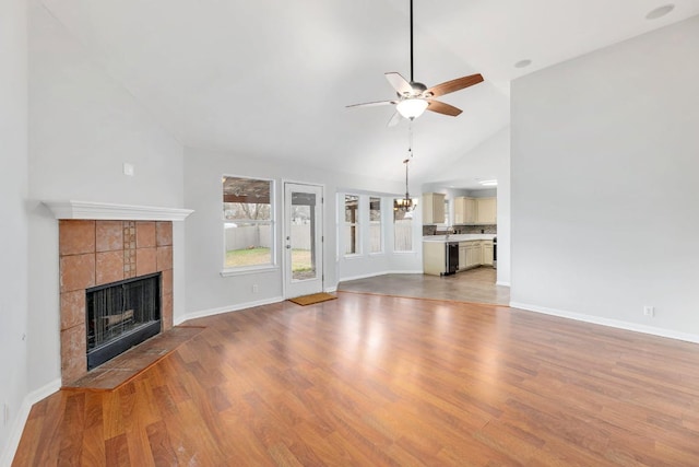 214 Crystal Knoll Blvd, Georgetown, TX 78626 - unfurnished living room with a fireplace, a ceiling fan, wood finished floors, high vaulted ceiling, and a chandelier