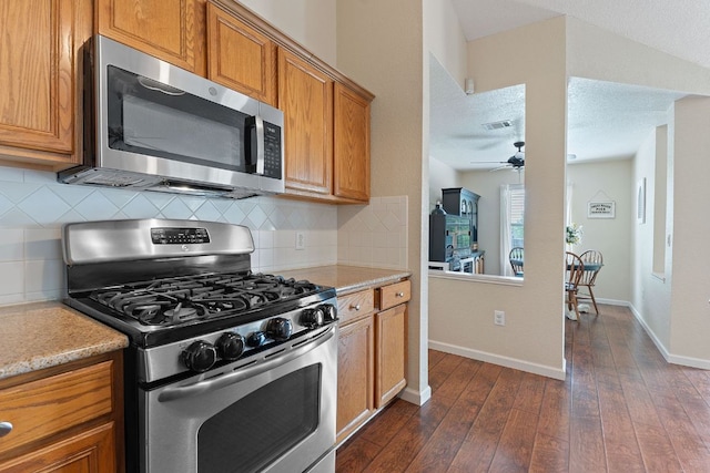 198 Prairie Springs Loop, Georgetown, TX 78626 - kitchen with dark wood finished floors, brown cabinetry, appliances with stainless steel finishes, and a ceiling fan