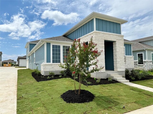 8516 Dongan Dr, Austin, TX 78744 - view of front of home featuring board and batten siding, stone siding, and a front lawn