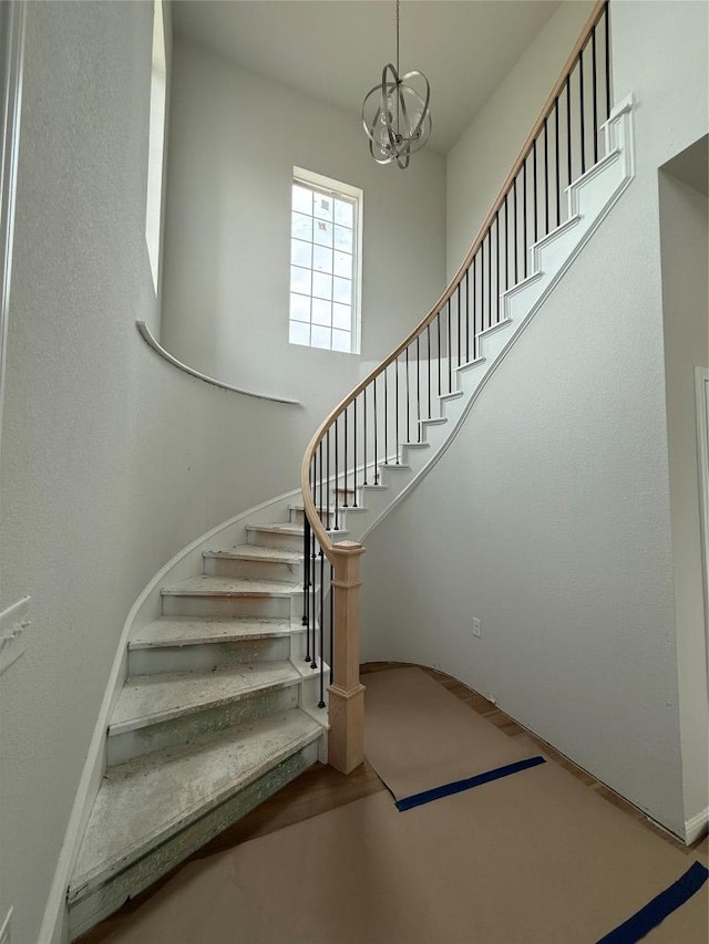 8600 Dongan Dr, Austin, TX 78744 - staircase featuring a towering ceiling, wood finished floors, and a notable chandelier