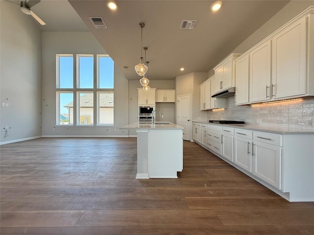 8600 Dongan Dr, Austin, TX 78744 - kitchen with stainless steel microwave, gas cooktop, recessed lighting, dark wood-style floors, and white cabinetry