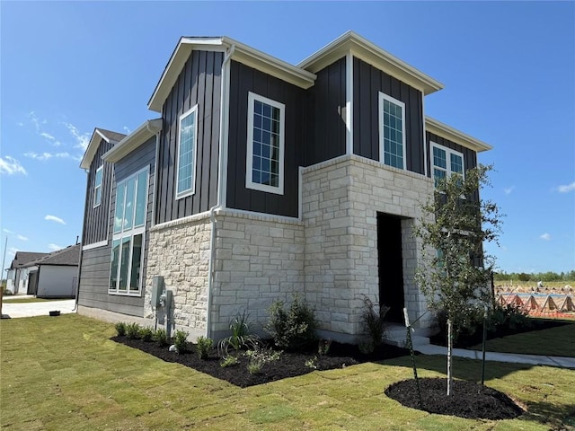 8600 Dongan Dr, Austin, TX 78744 - view of side of property with board and batten siding, stone siding, and a lawn