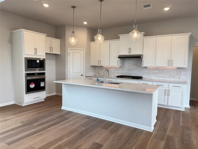8600 Dongan Dr, Austin, TX 78744 - kitchen with appliances with stainless steel finishes, light countertops, dark wood-style flooring, white cabinets, and recessed lighting