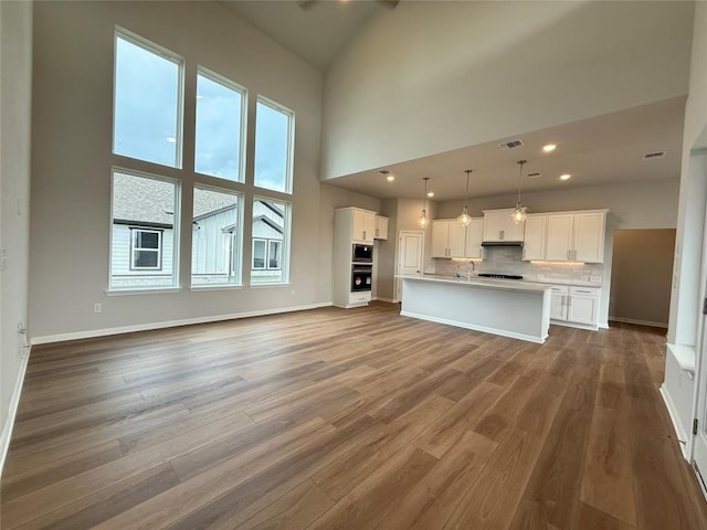 8600 Dongan Dr, Austin, TX 78744 - unfurnished living room with wood finished floors, a towering ceiling, and recessed lighting