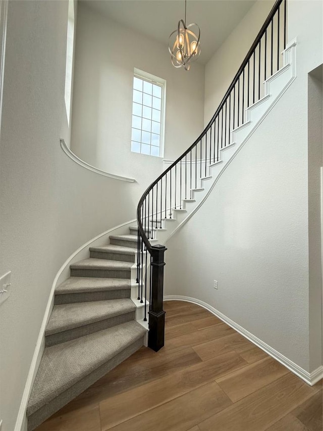8600 Dongan Dr, Austin, TX 78744 - stairway featuring wood finished floors, a chandelier, and a towering ceiling