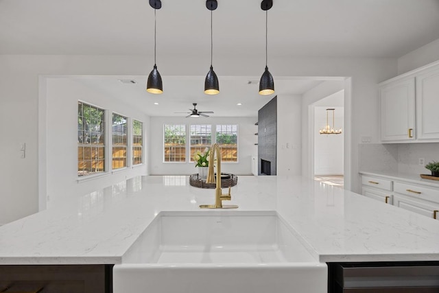 3505 Galena Hills Loop, Round Rock, TX 78681 - kitchen with a fireplace, light stone countertops, ceiling fan, white cabinets, and pendant lighting