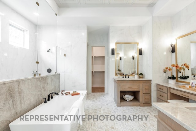 full bath featuring walk in shower, a freestanding bath, tile walls, vanity, and tile patterned flooring