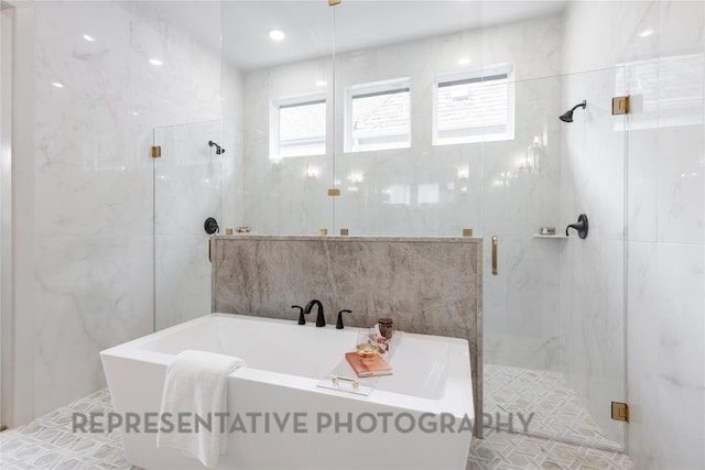 full bathroom featuring a marble finish shower, tile walls, and a soaking tub
