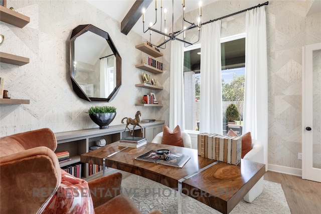 sitting room with beam ceiling, baseboards, light wood-type flooring, and an inviting chandelier