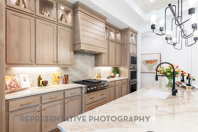 kitchen featuring appliances with stainless steel finishes, light stone counters, a sink, custom range hood, and backsplash