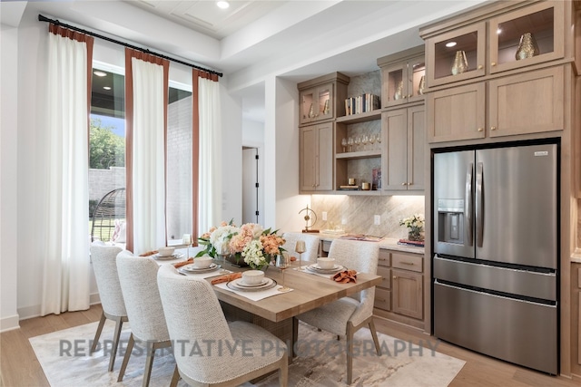 kitchen with light wood-type flooring, decorative backsplash, open shelves, and stainless steel refrigerator with ice dispenser