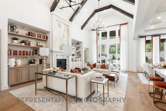 living area featuring high vaulted ceiling, a fireplace, beamed ceiling, light wood finished floors, and a notable chandelier