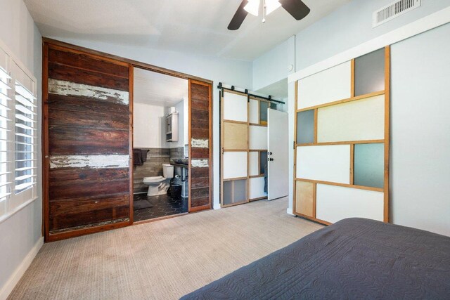 5310 Fort Clark Dr, Austin, TX 78745 - carpeted bedroom featuring a barn door, vaulted ceiling, ceiling fan, and connected bathroom