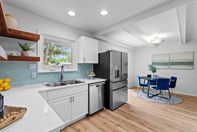 7003 Priscilla Dr, Austin, TX 78752 - kitchen with appliances with stainless steel finishes, beamed ceiling, decorative backsplash, light wood-style flooring, and white cabinetry