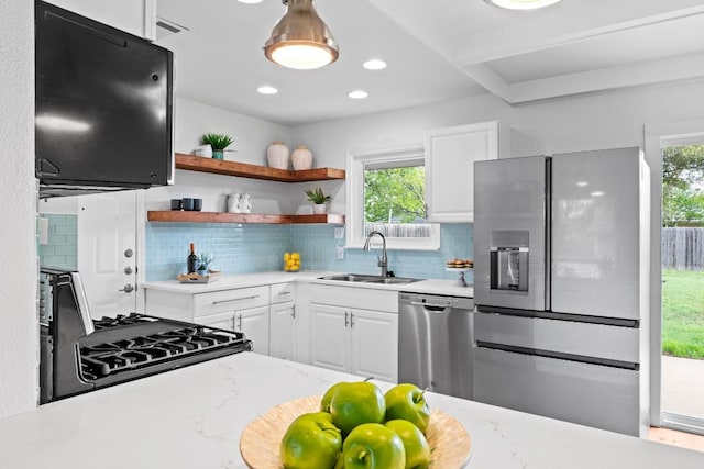 7003 Priscilla Dr, Austin, TX 78752 - kitchen with stainless steel dishwasher, refrigerator with ice dispenser, gas stove, white cabinetry, and decorative backsplash