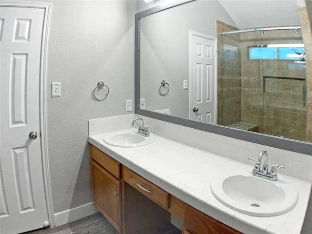 1608 Mallard Ln, Taylor, TX 76574 - bathroom with double vanity, a textured wall, a shower stall, wood finished floors, and lofted ceiling