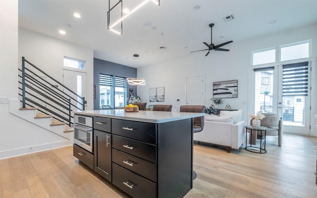 6221 Florencia Ln, Austin, TX 78724 - kitchen with light wood-type flooring, a ceiling fan, oven, a center island, and light countertops