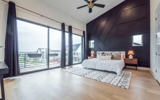 6221 Florencia Ln, Austin, TX 78724 - bedroom featuring wood finished floors, access to outside, an accent wall, high vaulted ceiling, and a ceiling fan