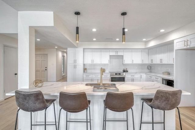 313 Lucy Ln, Horseshoe Bay, TX 78657 - kitchen with stainless steel range with electric cooktop, a sink, light wood finished floors, white cabinets, and decorative backsplash