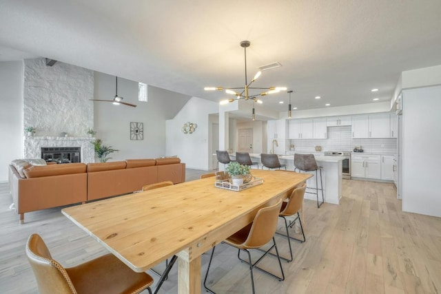 313 Lucy Ln, Horseshoe Bay, TX 78657 - dining area featuring light wood-style floors, a chandelier, a large fireplace, and recessed lighting