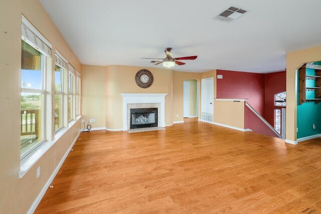 4142 Rockwood Dr, Lago Vista, TX 78645 - unfurnished living room with light wood-style flooring, a ceiling fan, a tile fireplace, and arched walkways