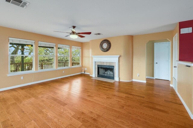 4142 Rockwood Dr, Lago Vista, TX 78645 - unfurnished living room featuring a ceiling fan, light wood finished floors, a tiled fireplace, and arched walkways
