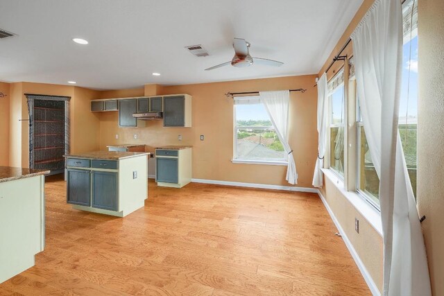 4142 Rockwood Dr, Lago Vista, TX 78645 - kitchen featuring under cabinet range hood, light wood-style floors, a ceiling fan, recessed lighting, and a center island