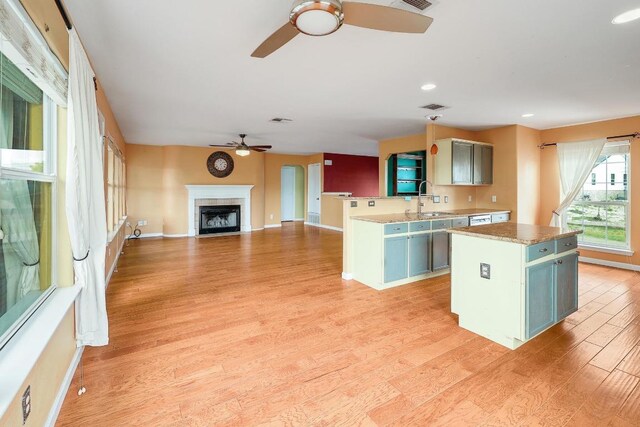 4142 Rockwood Dr, Lago Vista, TX 78645 - kitchen with a ceiling fan, light wood-style flooring, a kitchen island, a fireplace, and recessed lighting