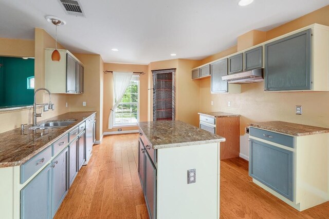 4142 Rockwood Dr, Lago Vista, TX 78645 - kitchen featuring under cabinet range hood, light wood finished floors, stone counters, a kitchen island, and stainless steel dishwasher