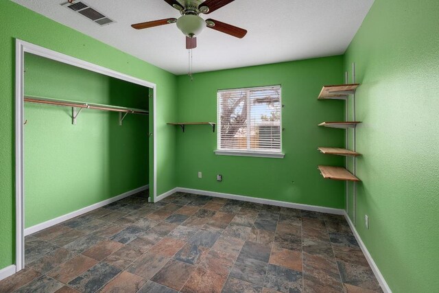 4142 Rockwood Dr, Lago Vista, TX 78645 - unfurnished bedroom featuring stone finish floors, a closet, and ceiling fan